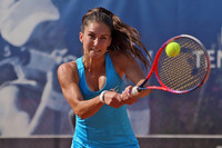 Eine junge Frau mit Tennisschläger mitten im Ausholen und kurz davor, den Ball zu schlagen