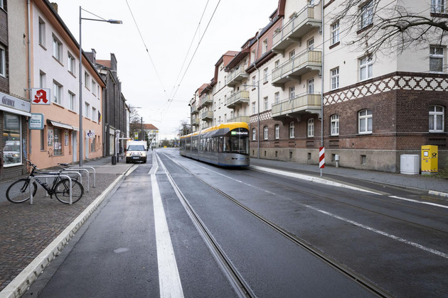 Auf der neu asphaltierten Ratzelstraße fährt eine Straßenbahn, links und rechts Hausfassaden.