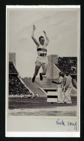 Schwarz-weiß-Bild eines Sportlers beim Weitspringen bei einem öffentlichen Wettkampf