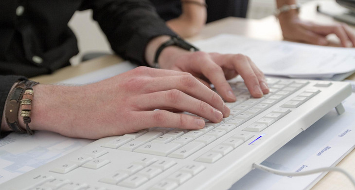 Ein Mann schreibt auf einer Computertastatur